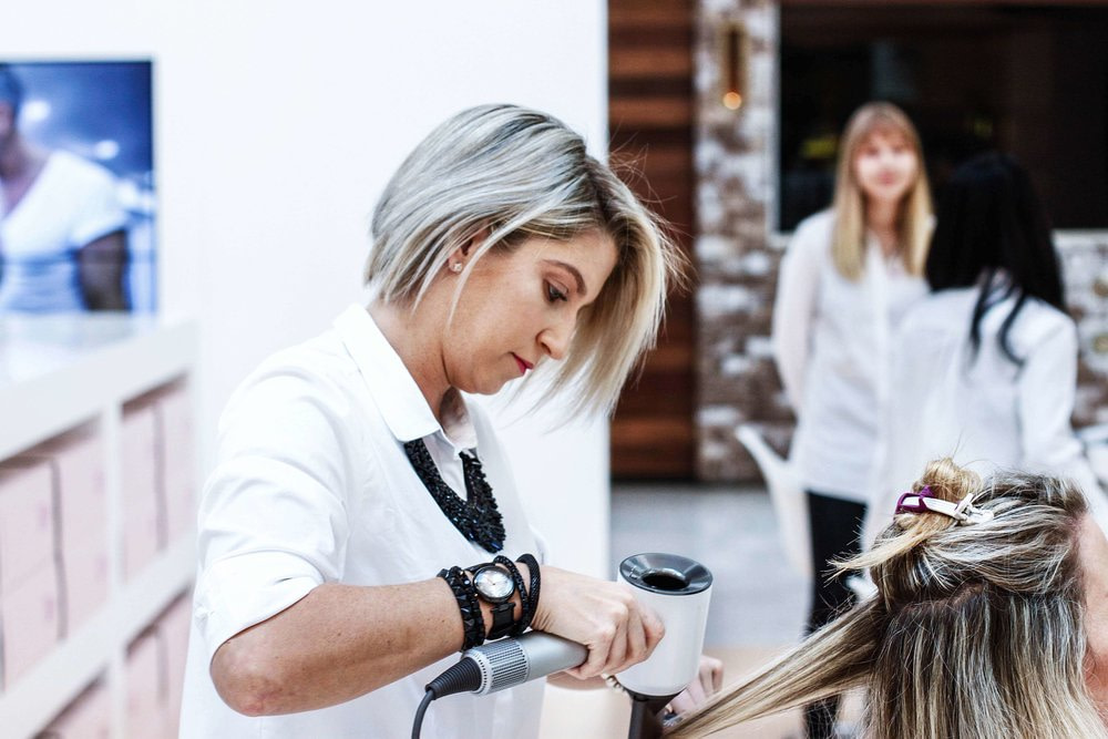 Mobile hairdresser working on ladies hair, drying with hairdryer